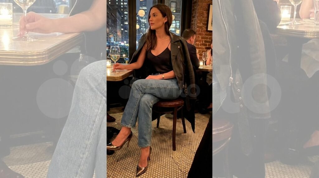 A a an and at black camisole, draped heels. her jacket jeans, leather medium-wash metallic over pointed restaurant shoulders, silk sitting straight-leg upscale wearing woman
