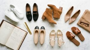 Capsule shoe wardrobe essentials flat lay featuring white sneakers, black loafers, ankle boots, and pumps.