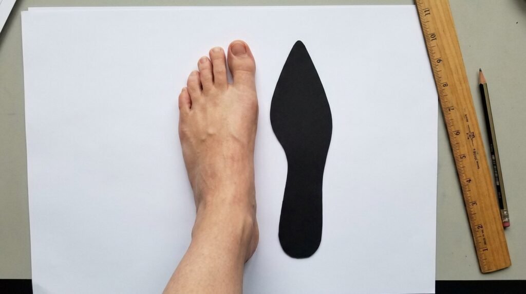 Top-down comparison of natural foot width versus a pointed-toe shoe silhouette.