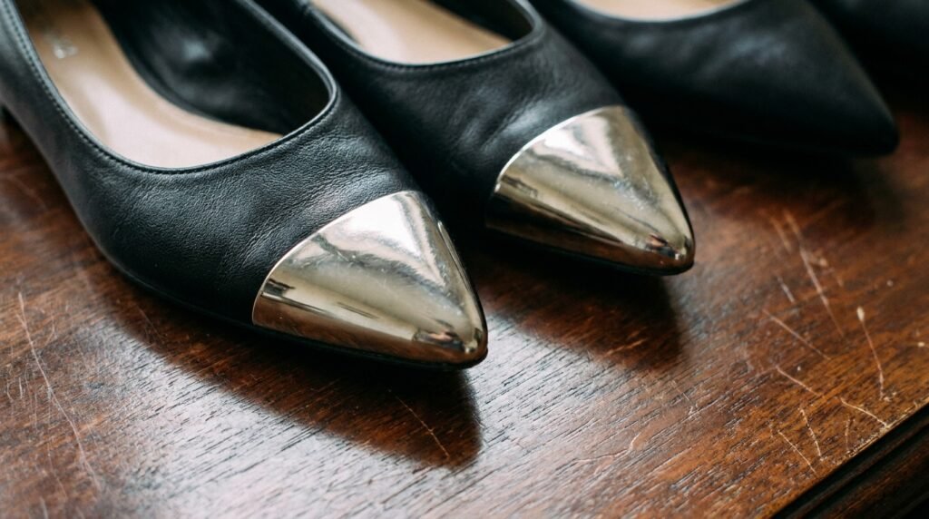 Pointed-toe black leather flats with silver metallic toe cap accents.