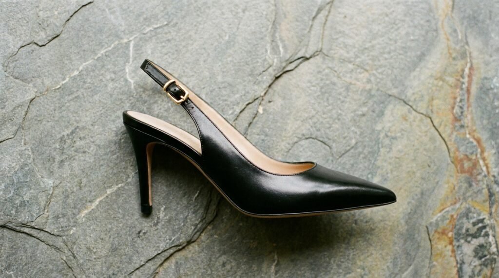 Black leather pointed-toe slingback heels with subtle gold buckle detail.